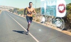 Athletic man jogging on open road with monitor