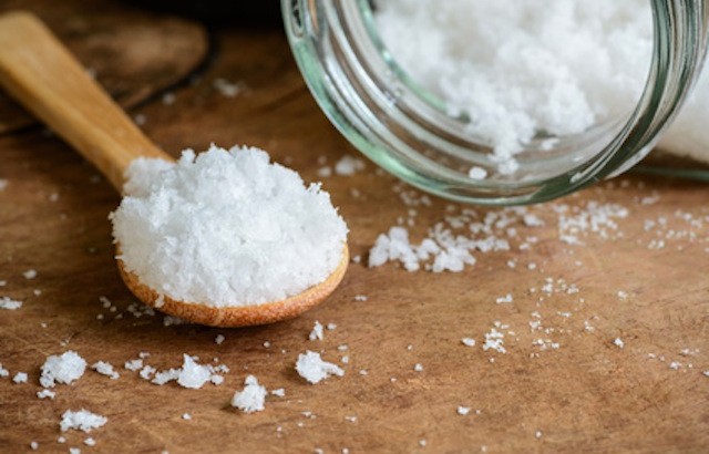 Sea salt and wooden spoon on wooden table